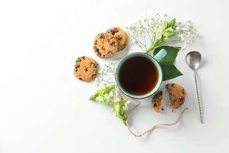 Beautiful flat lay composition with cup of tea and flowers and cookies on white backgroundの写真素材
