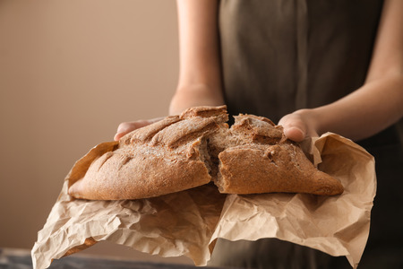 Woman breaking fresh tasty bread, closeup