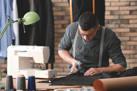 Young tailor cutting fabric in atelierの写真素材