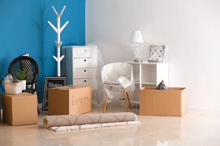 Carton boxes and interior items on floor in room. Moving house concept