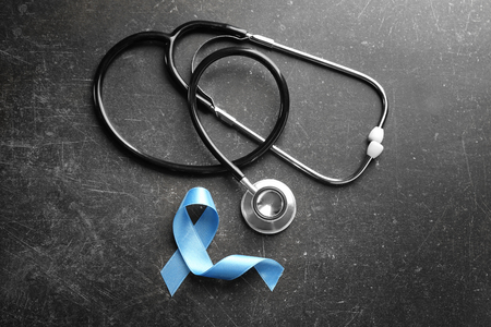 Blue ribbon and stethoscope on dark background. Prostate cancer conceptの写真素材