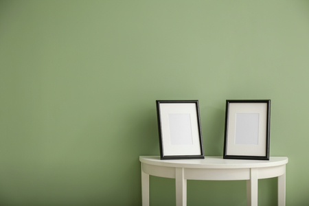 Photo frames on white table against color backgroundの写真素材