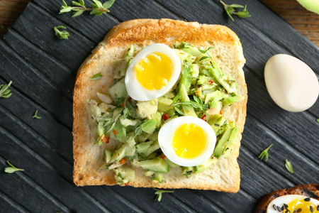 Tasty toast with avocado on wooden board