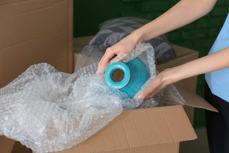 Woman packing carton box indoors. Moving house concept