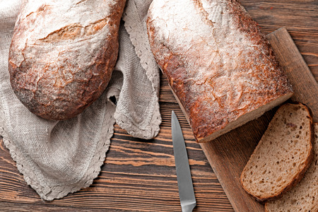 Knife and board with cut fresh tasty bread on wooden table