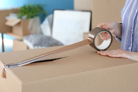 Woman packing carton box indoors. Moving house conceptの写真素材