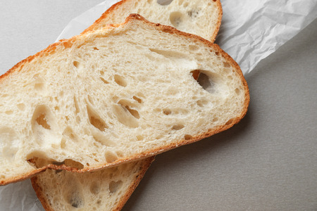 Sliced tasty bread on grey background, closeup