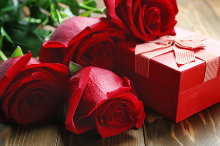 Gift box and beautiful roses on wooden background, closeupの写真素材