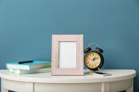 Composition with photo frame on white table against color background