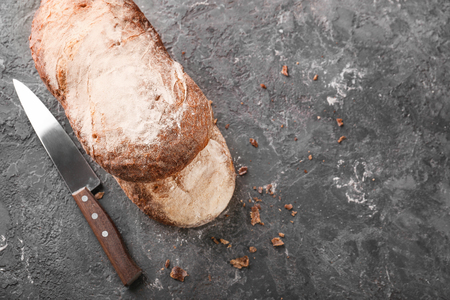 Knife and fresh tasty bread on grey backgroundの写真素材