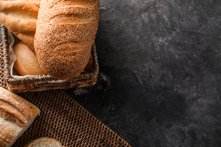 Wicker basket and mat with fresh tasty bread on tableの写真素材