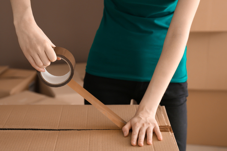 Woman packing carton box indoors. Moving house conceptの写真素材