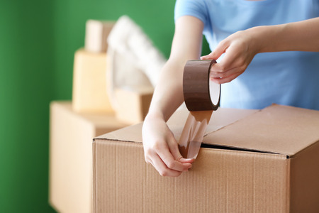 Woman packing carton box indoors. Moving house conceptの写真素材
