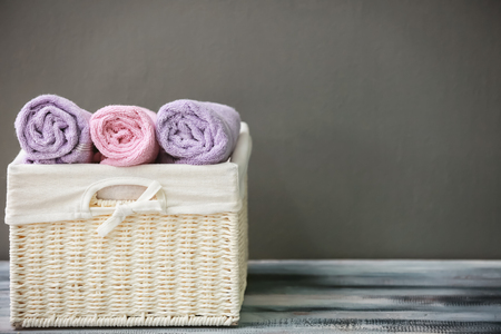 Wicker basket with towels on wooden table against grey backgroundの写真素材