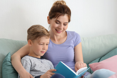 Mother and her son reading book together at homeの写真素材