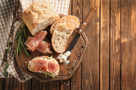 Tasty sandwich with prosciutto and sliced bread on wooden boardの写真素材