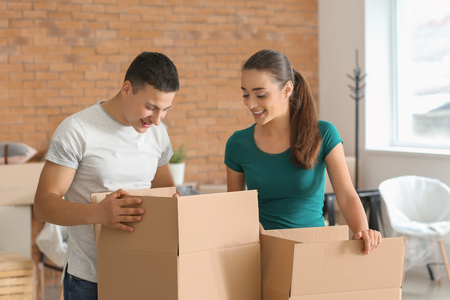 Young couple with boxes indoors. Moving into new houseの写真素材