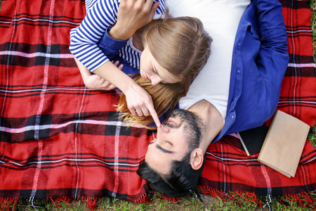 Happy young couple lying on plaid in parkの写真素材