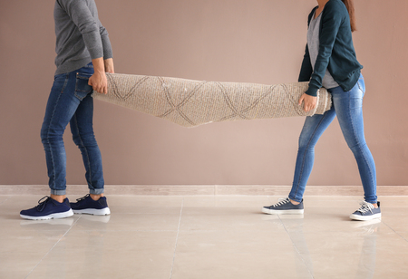 Young couple carrying carpet indoors. Moving into new houseの写真素材