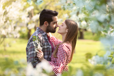 Happy young couple near blooming tree in park on spring dayの写真素材