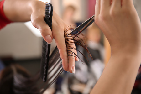 Professional hairdresser working with client in beauty salon, closeup