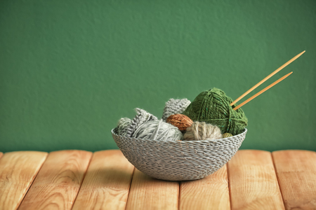 Basket with knitting yarn and needles on table against color backgroundの写真素材