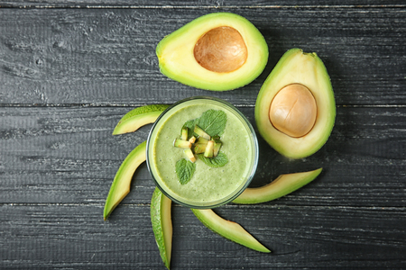 Ripe avocados and glass of tasty smoothie on wooden backgroundの写真素材