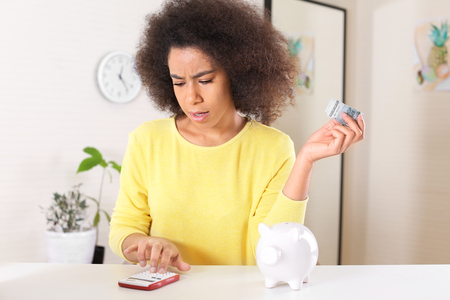 Young African-American woman counting money at home. Savings conceptの写真素材