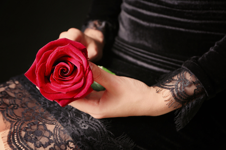 Woman holding beautiful rose on dark background, closeupの写真素材