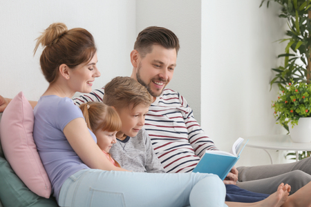 Happy family reading book together at homeの写真素材