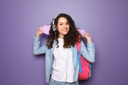 Beautiful young woman with skateboard on color backgroundの写真素材