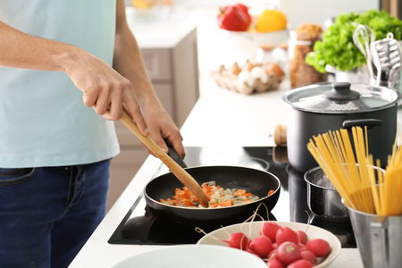 Young man cooking in kitchenの写真素材