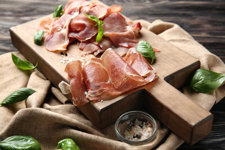 Sliced tasty prosciutto on wooden boardの写真素材