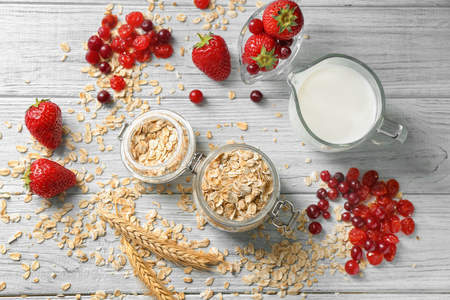 Composition with oatmeal flakes, milk and berries on wooden tableの写真素材