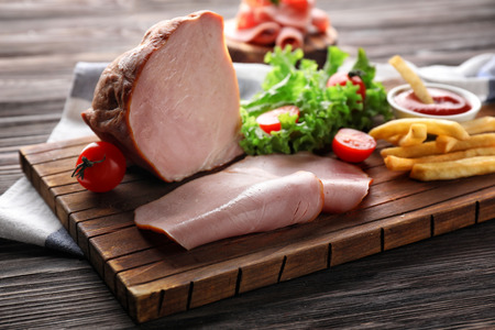 Board with delicious sliced ham on wooden tableの写真素材