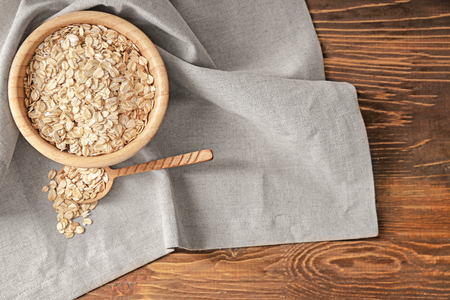 Bowl and spoon with oatmeal flakes on tableの写真素材