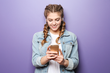 Beautiful young woman listening to music on color backgroundの写真素材