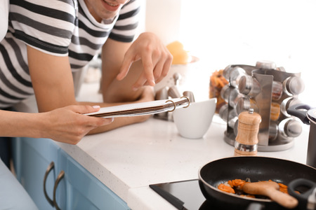 Young couple reading recipe book in kitchenの写真素材