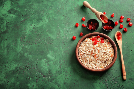 Bowl with oatmeal flakes and dry berries on tableの写真素材