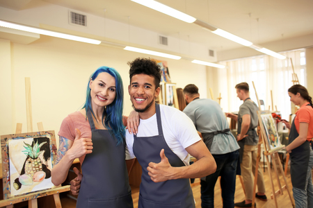 Young students showing thumb-up gesture in art schoolの写真素材