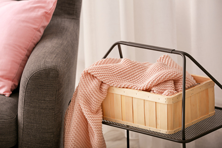 Basket with knitted plaid on table indoorsの写真素材