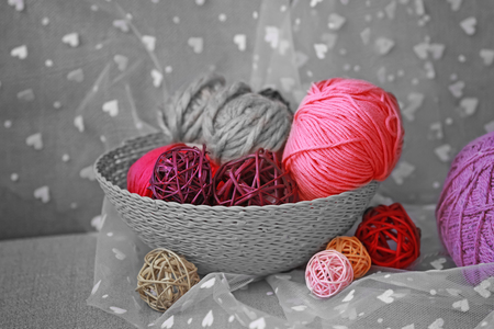 Basket with balls of knitting yarn and transparent fabric on sofaの写真素材