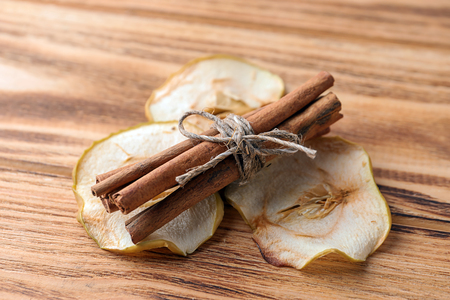 Cinnamon sticks and dried apple slices on wooden backgroundの写真素材