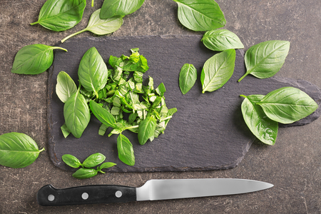 Slate board with fresh basil and knife on grey backgroundの写真素材