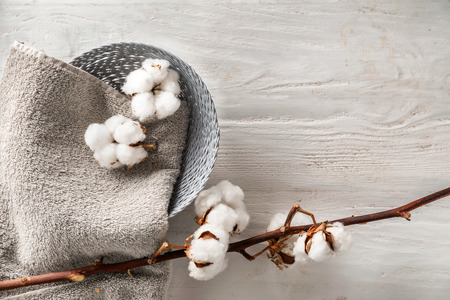 Basket with towel and cotton flowers on wooden backgroundの写真素材