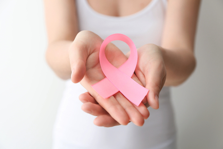 Woman holding pink ribbon on light background, closeup. Breast cancer awareness conceptの写真素材