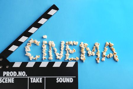 Clapperboard and word CINEMA made of popcorn on color backgroundの写真素材