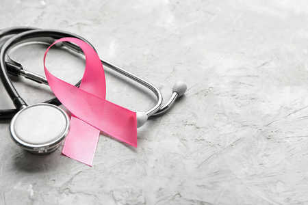 Pink ribbon and stethoscope on grey background. Breast cancer awareness conceptの写真素材