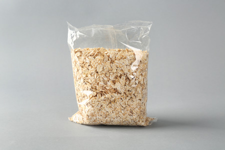 Package with raw oatmeal on light backgroundの写真素材