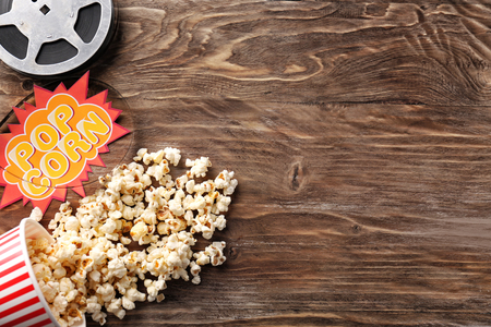 Composition with tasty popcorn and film reel on wooden backgroundの写真素材